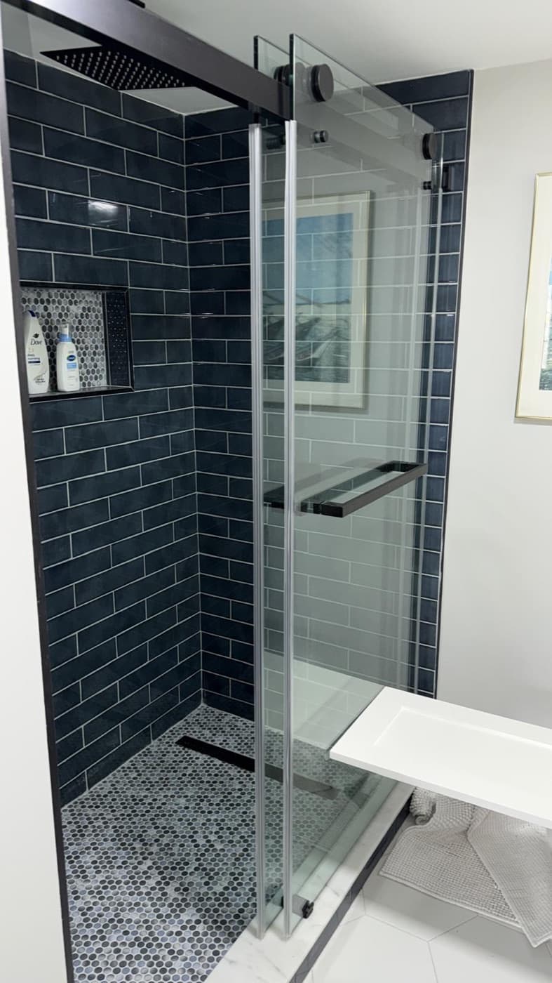 Remodeled bathroom with dark subway tile and a glass walk-in shower