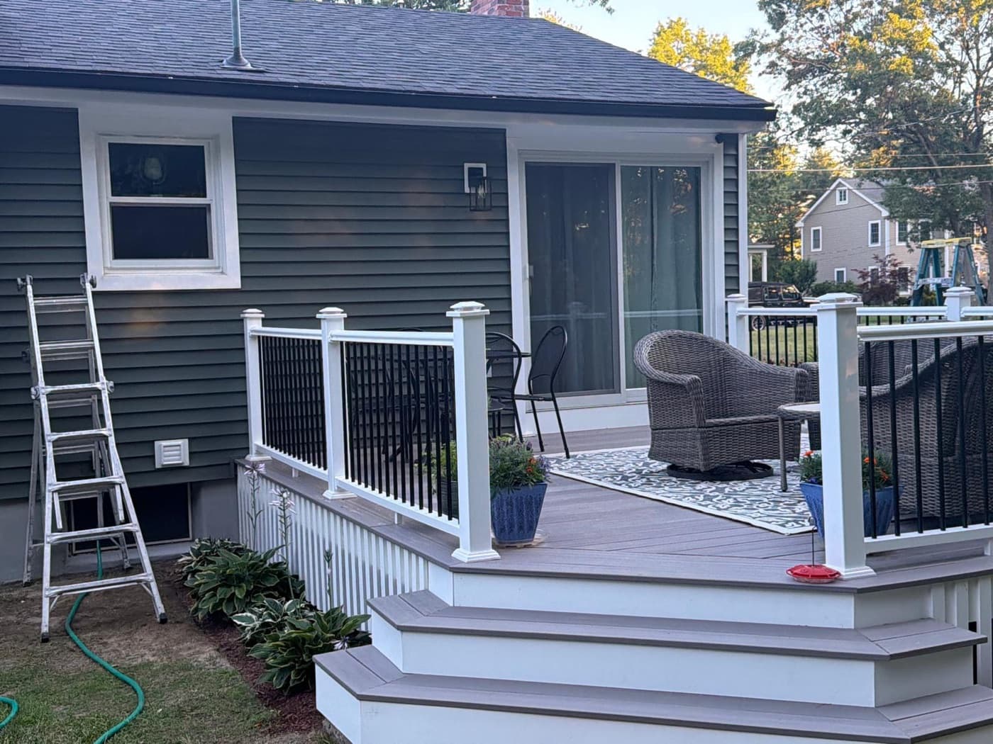 Backyard composite deck with gray boards and black aluminum railings on a New England home