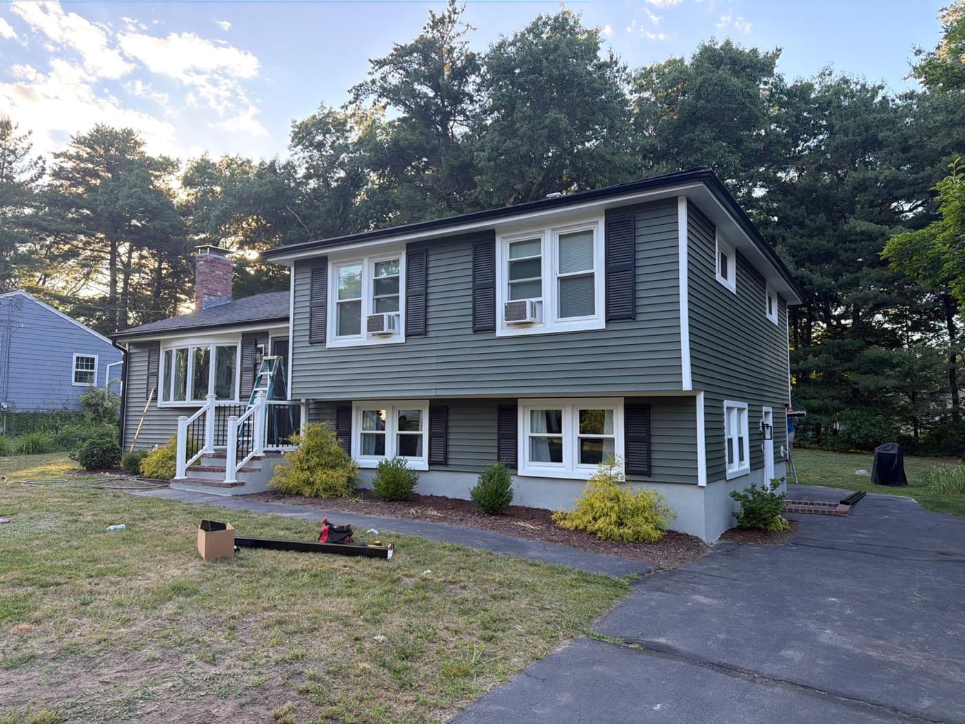 Freshly installed siding on the front of a green single-family home in Greater Boston