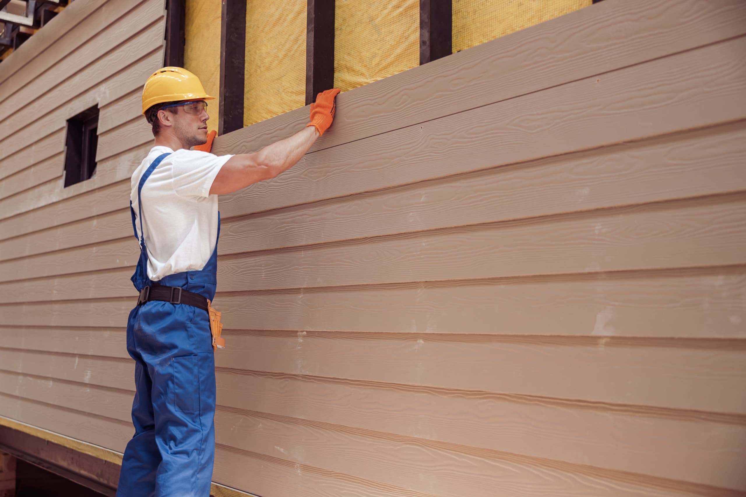 Crew member installing siding on a home